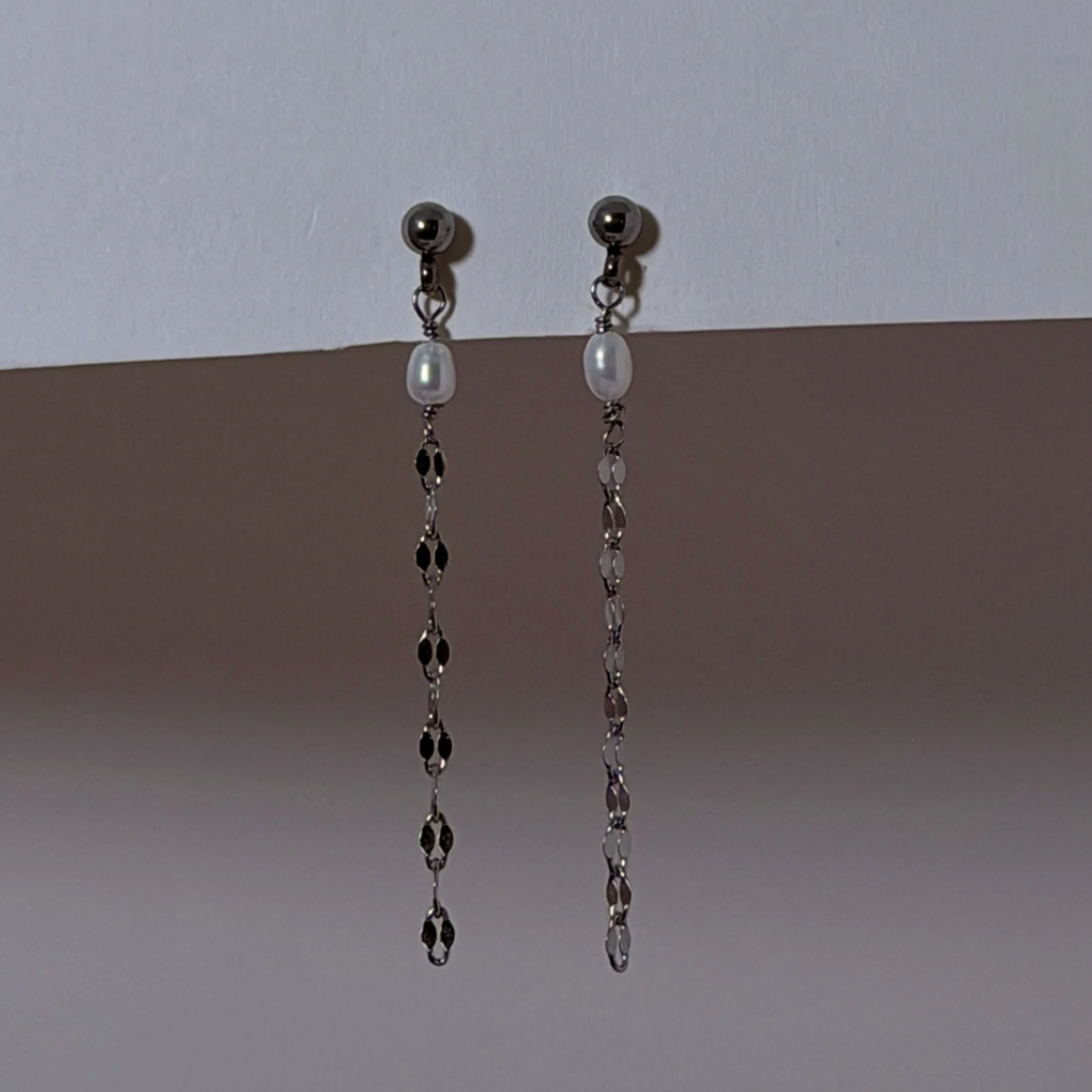 Pair of dangling earrings with pearls on a gradient background