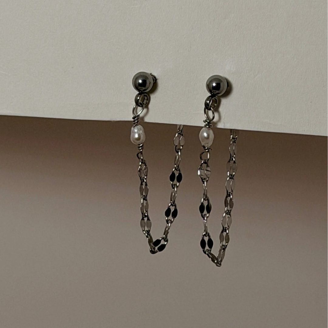Pair of silver chain earrings on a beige background